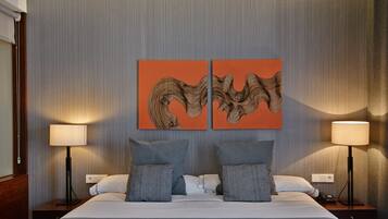 A hotel room with a large bed, two bedside tables, two lamps, and two wall-mounted artworks.