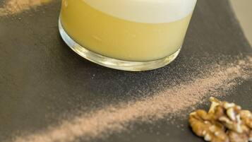 Un postre en un vaso, con una galleta de obleas encima, sobre una superficie oscura con nueces esparcidas.