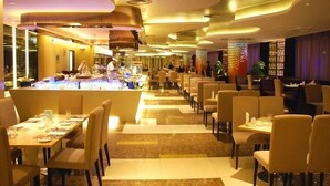 A modern restaurant with a long counter, multiple dining tables, and a variety of seating options. - Hengdong Business Hotel - Guangzhou (Guangzhou)