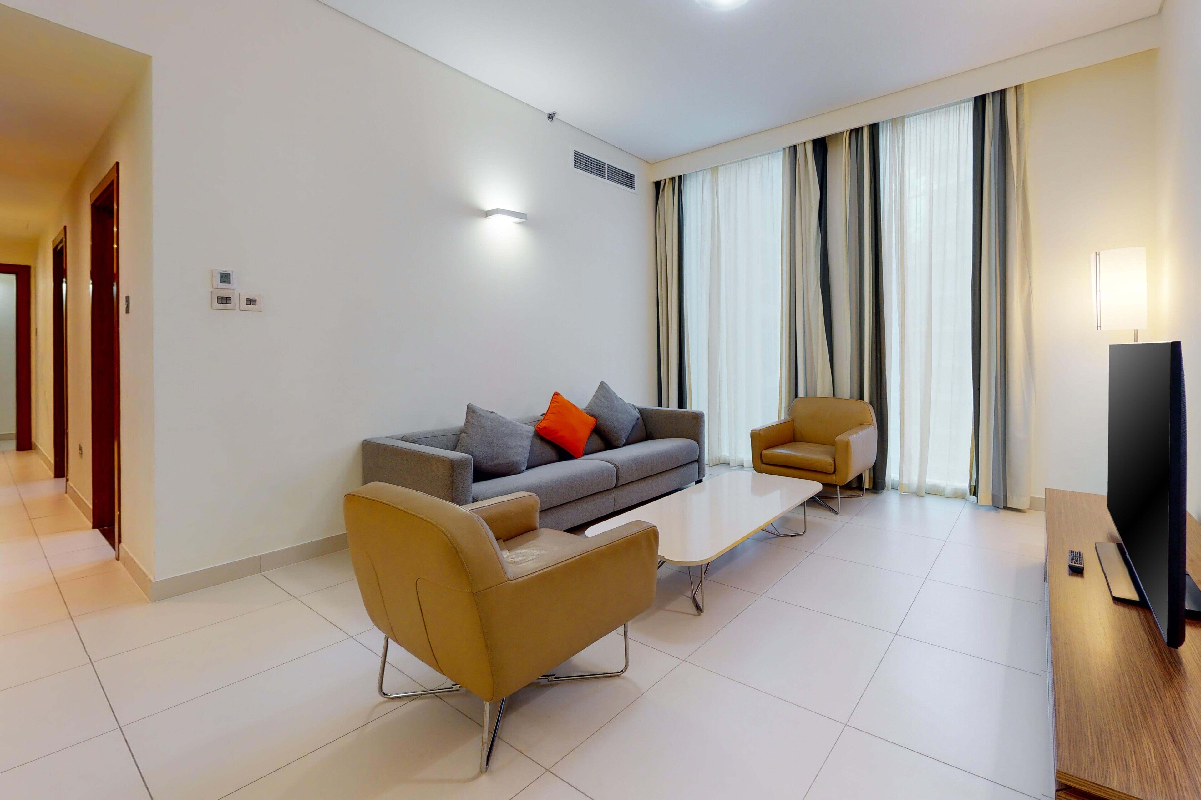 A modern living room with a sofa, armchair, coffee table, and TV.