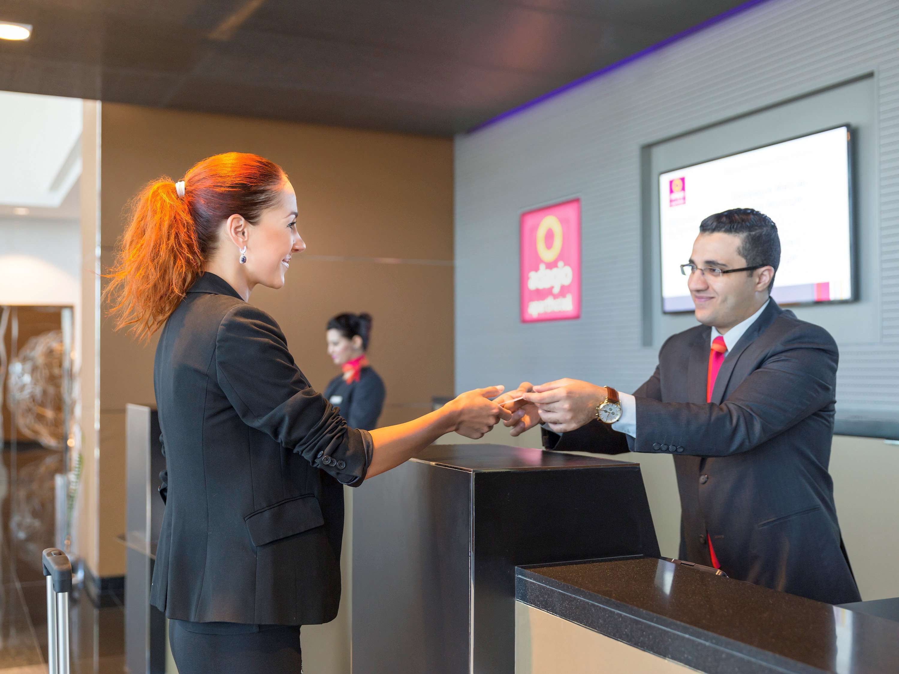 A reception desk with a man and a woman exchanging a document.