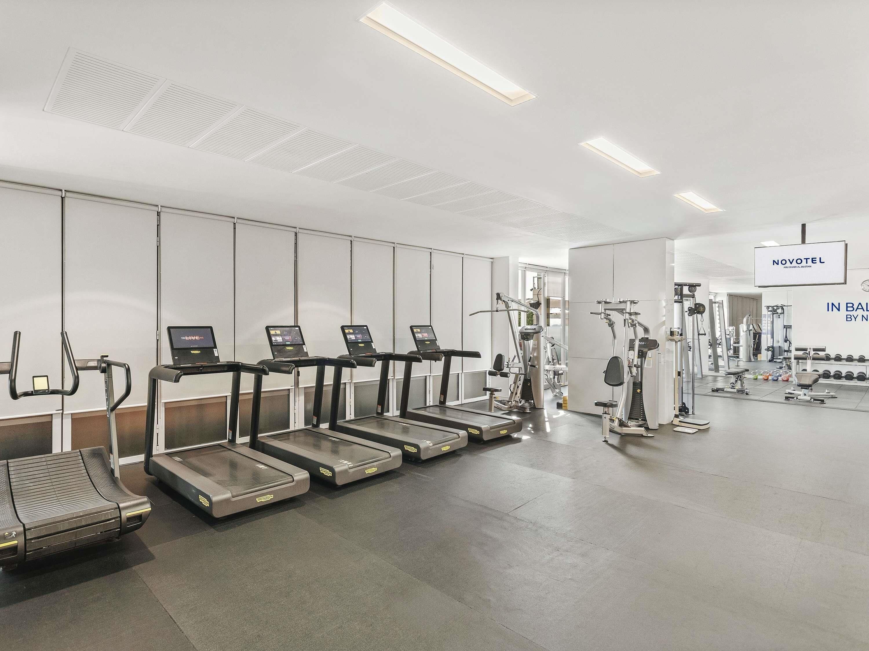 Un gimnasio con cintas de correr, elípticas y equipo de pesas.