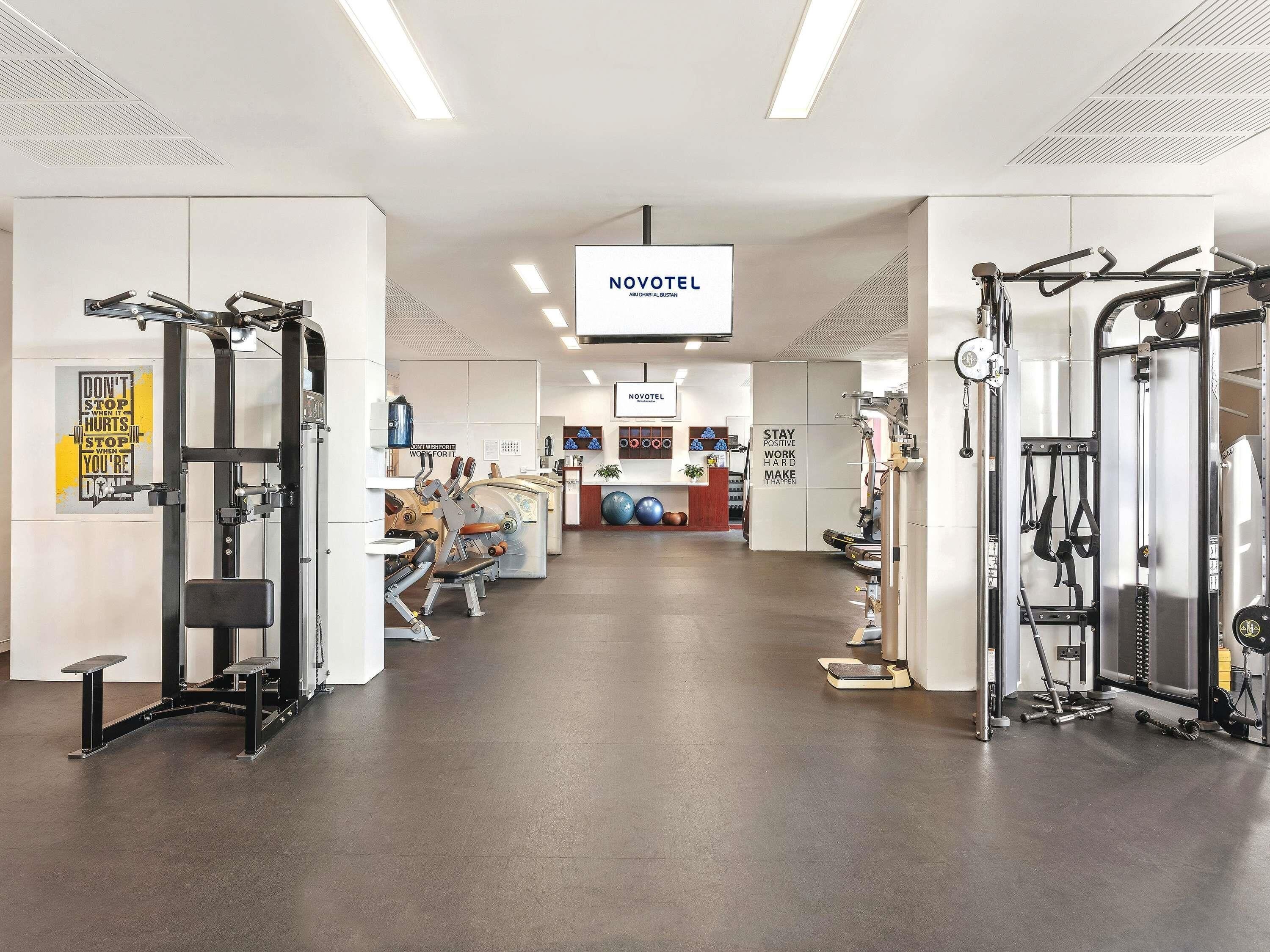A modern gym with various exercise equipment, motivational posters, and a reception area.