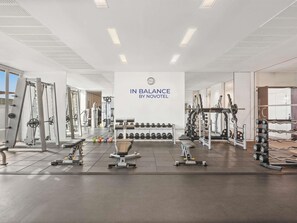 A gym with various exercise equipment, a wall sign reading 'IN BALANCE BY NOVOTEL', and a view of the outside.