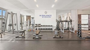 A gym with various exercise equipment, a wall clock, and a sign that reads 'IN BALANCE BY NOVOTEL'. - Aparthotel Adagio Abu Dhabi Al Bustan (Abu Dhabi)