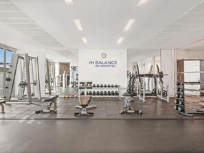 A gym with various exercise equipment, a wall clock, and a sign that reads 'IN BALANCE BY NOVOTEL'. - Aparthotel Adagio Abu Dhabi Al Bustan (Abu Dhabi)