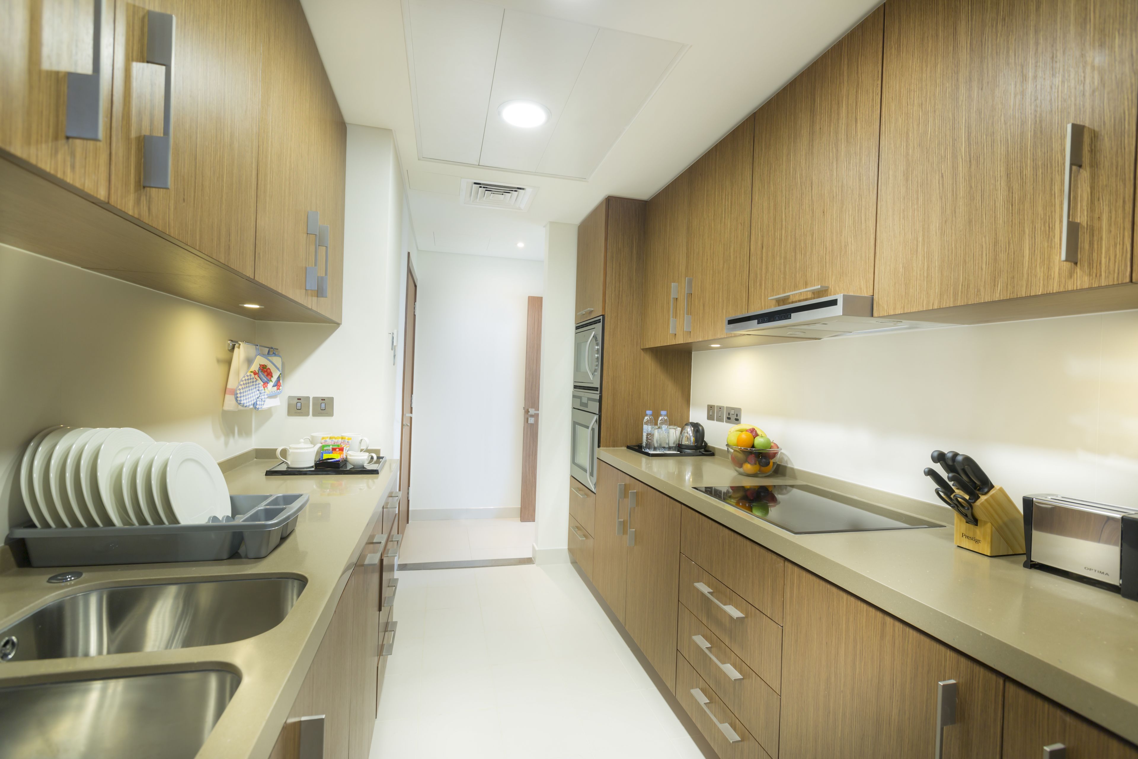 A modern kitchen with stainless steel appliances, wooden cabinets, and a countertop with a knife block and toaster.