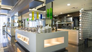 A modern hotel lobby with a central reception area, a glass display case with various items, and a kitchen area in the background. - Aparthotel Adagio Abu Dhabi Al Bustan (Abu Dhabi)