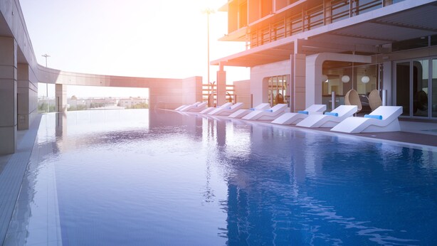 A swimming pool with lounge chairs and a modern building in the background. - Aparthotel Adagio Abu Dhabi Al Bustan (Abu Dhabi)