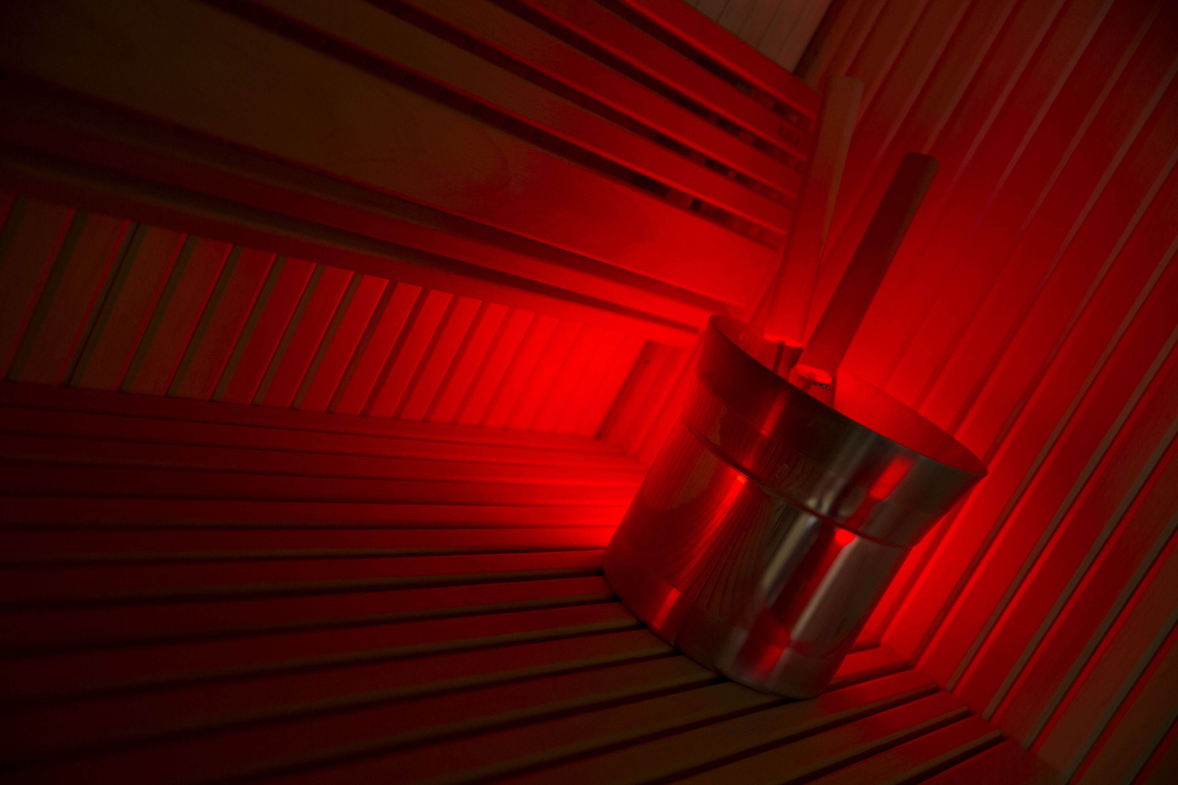 Une poubelle métallique dans une pièce éclairée de lumière rouge, dont les murs en bois sont inclinés.