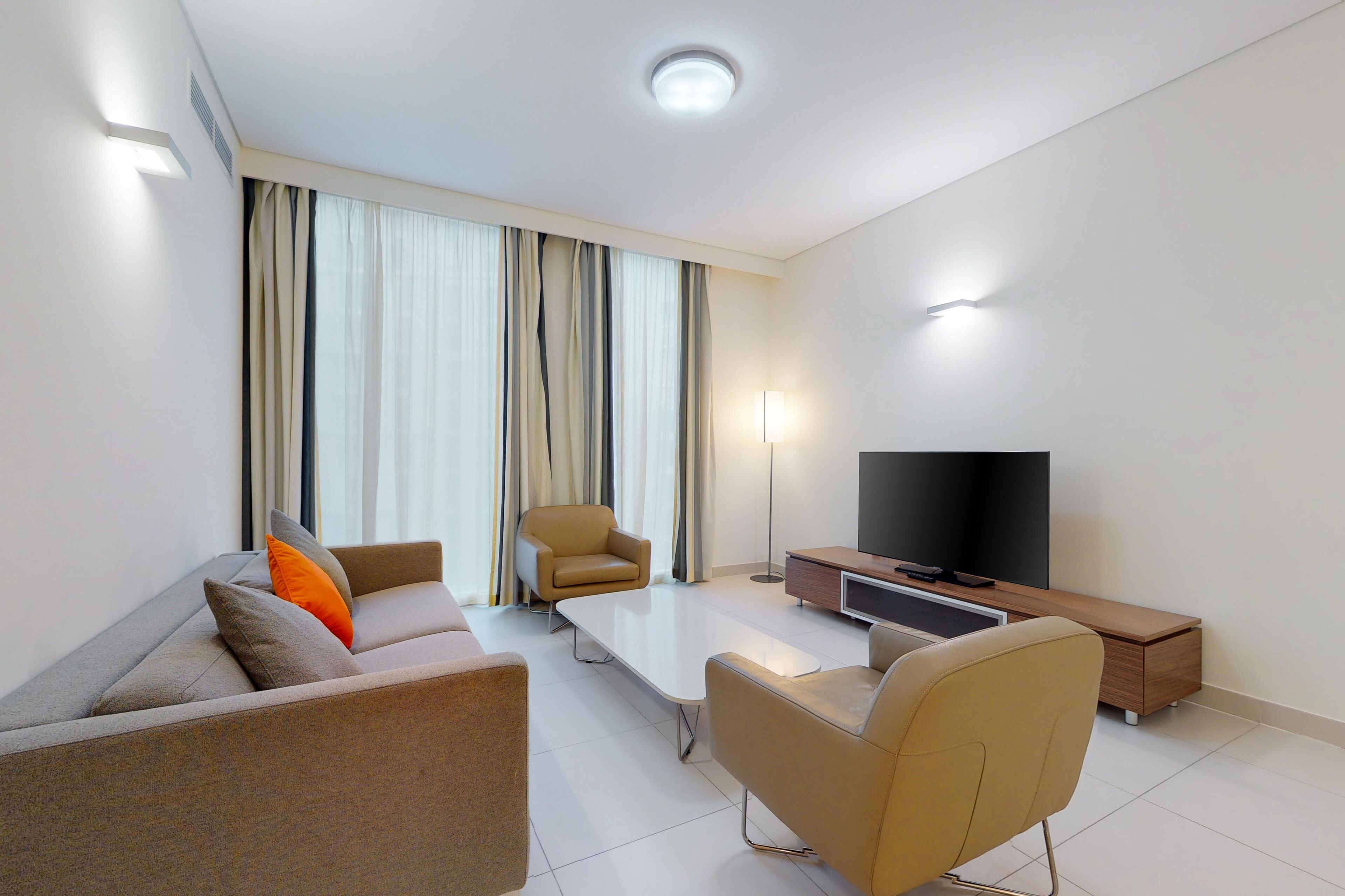A modern living room with a sofa, two armchairs, a coffee table, a TV, and a wooden side table.