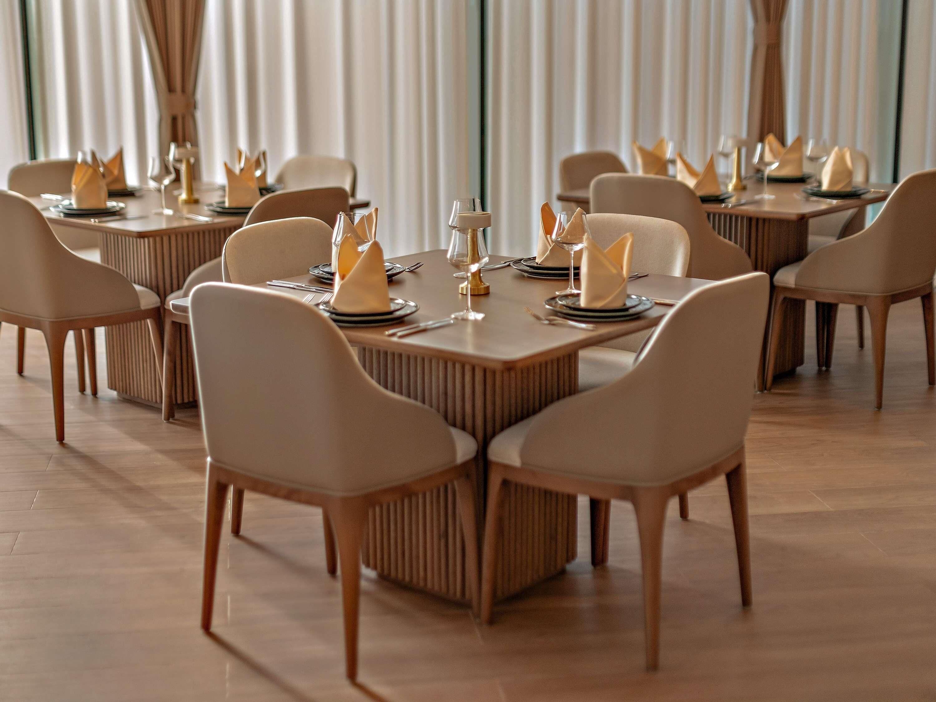 A dining area with rectangular tables, beige chairs, and a modern, minimalist design.