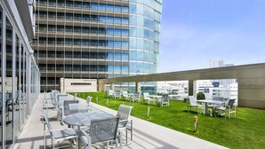 A rooftop terrace with outdoor seating and a view of a modern building. - Aparthotel Adagio Abu Dhabi Al Bustan (Abu Dhabi)