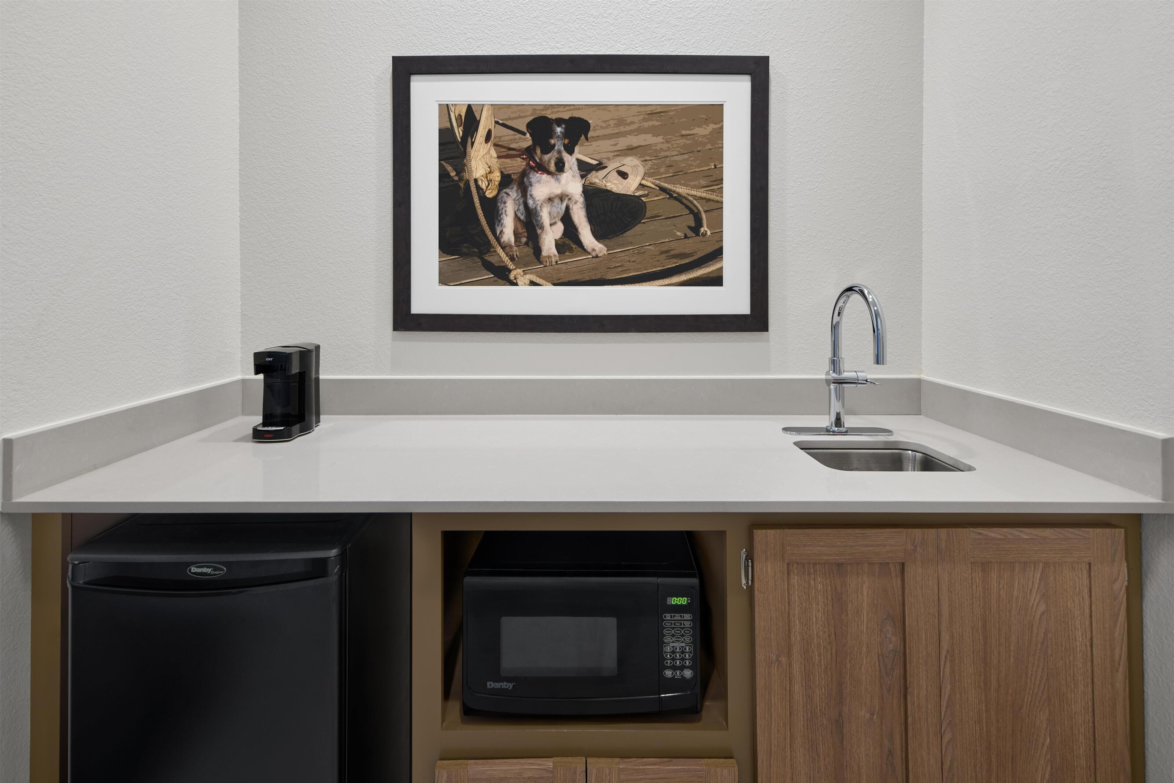Una cocina compacta con microondas, un lavabo y un refrigerador pequeño.