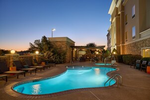 Una piscina al aire libre, sombrillas, sillones reclinables de piscina