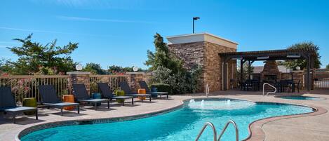 A swimming pool with lounge chairs and a covered seating area.