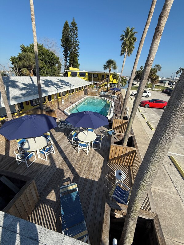 A pool area with two pools, lounge chairs, umbrellas, and a wooden deck. - Barefoot Bay Resort & Marina (Clearwater Beach)