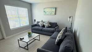 Ein modernes Wohnzimmer mit grauem Sofa, einem Couchtisch und einem Gemälde an der Wand.
