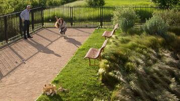 Relax on the grassy lawn surrounded by lush greenery, with two benches for a peaceful retreat.