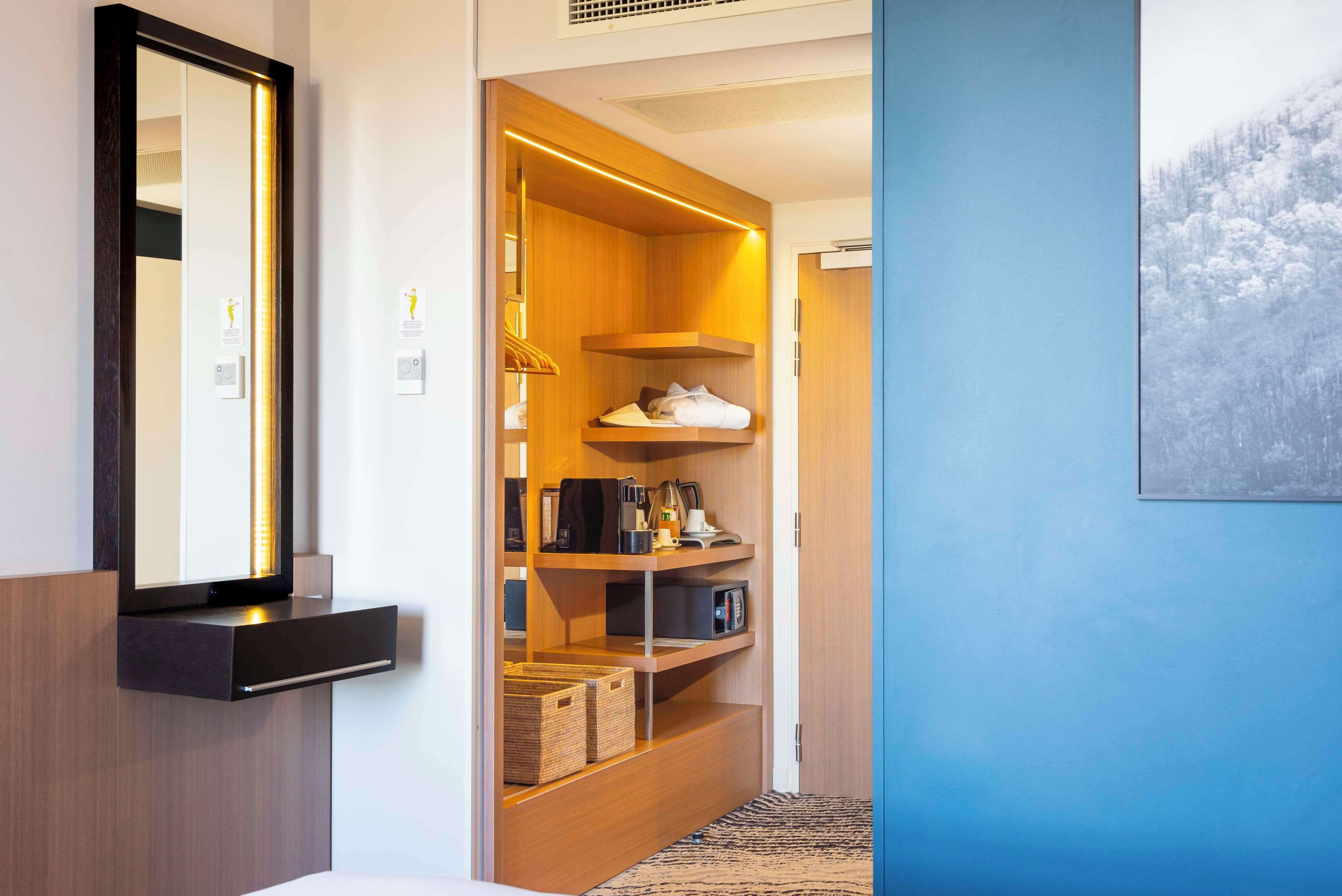 A modern closet with built-in shelves and a hanging shoe rack, a mirror, and a framed picture on the wall.