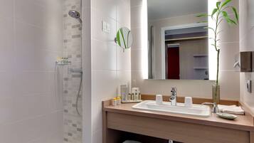 A modern bathroom with a shower, a sink with a mirror, and a potted plant.