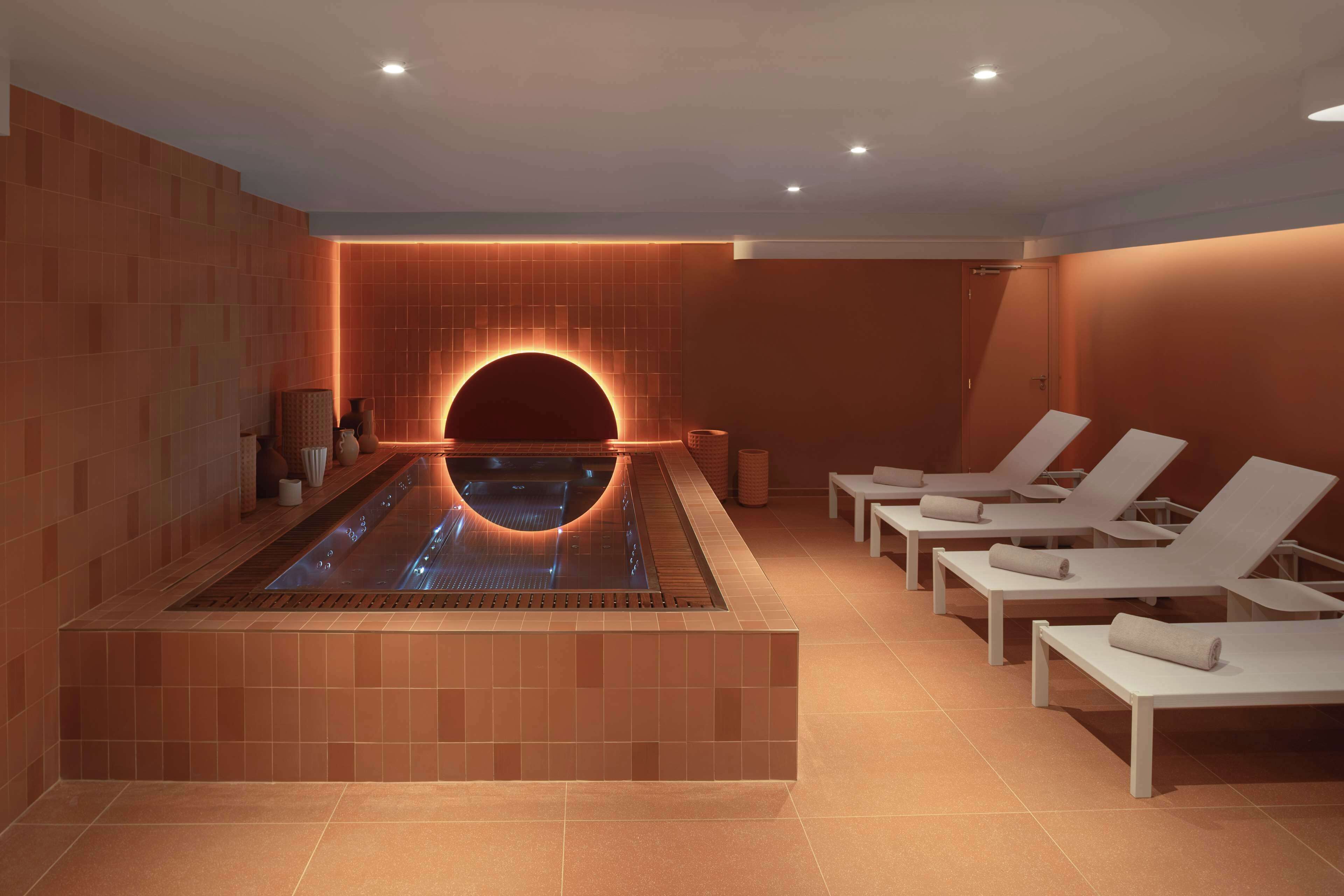 A spa area with a heated pool, lounge chairs, and a wall-mounted massage chair.