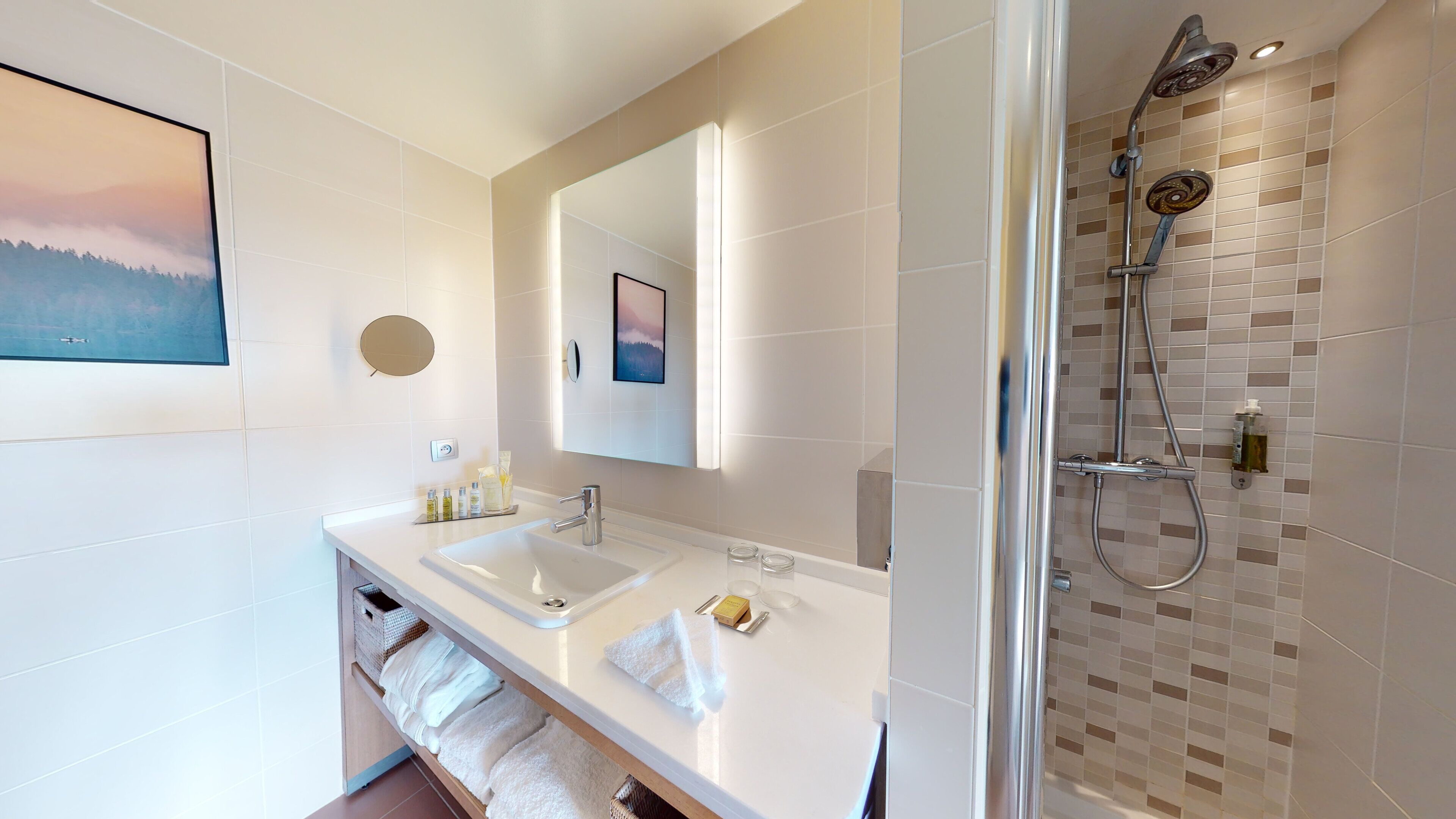 Un baño moderno con dos lavamanos, un espejo grande y una ducha con pared de azulejos.