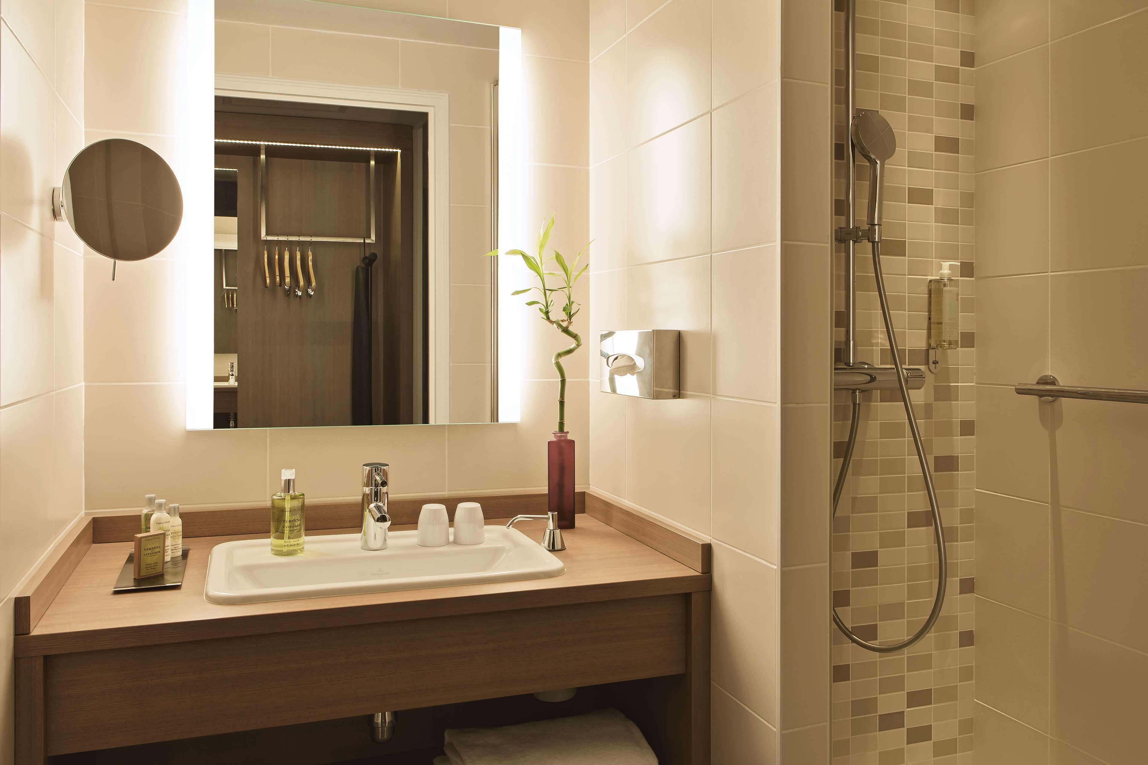 Une salle de bain équipée d’un lavabo, d’un miroir, d’articles de toilette et d’une douche.