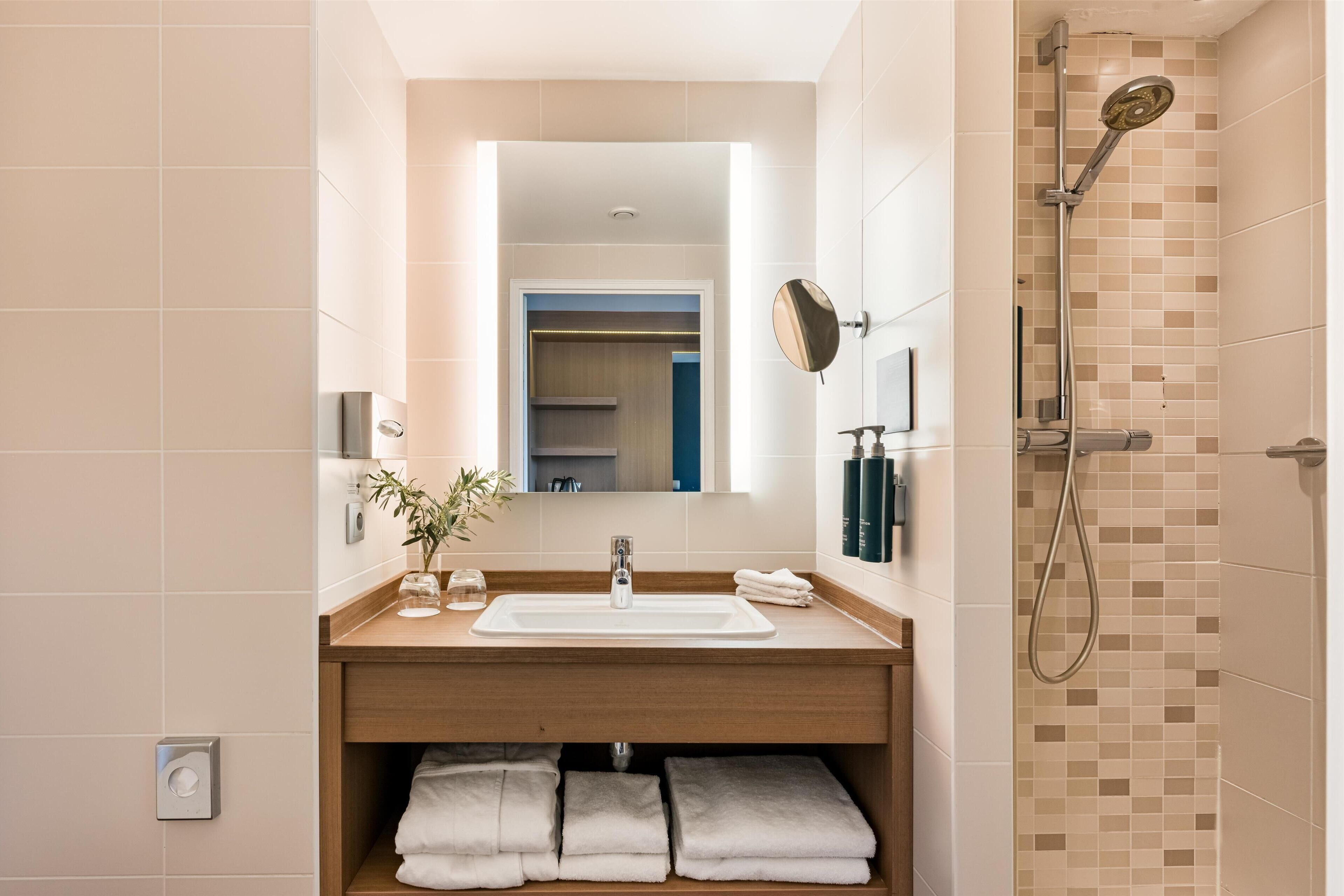 A modern bathroom with a sink, mirror, and shower.