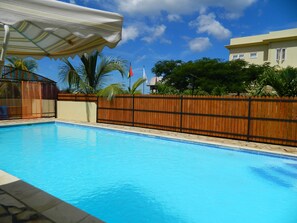 Een buitenzwembad, ligstoelen bij het zwembad