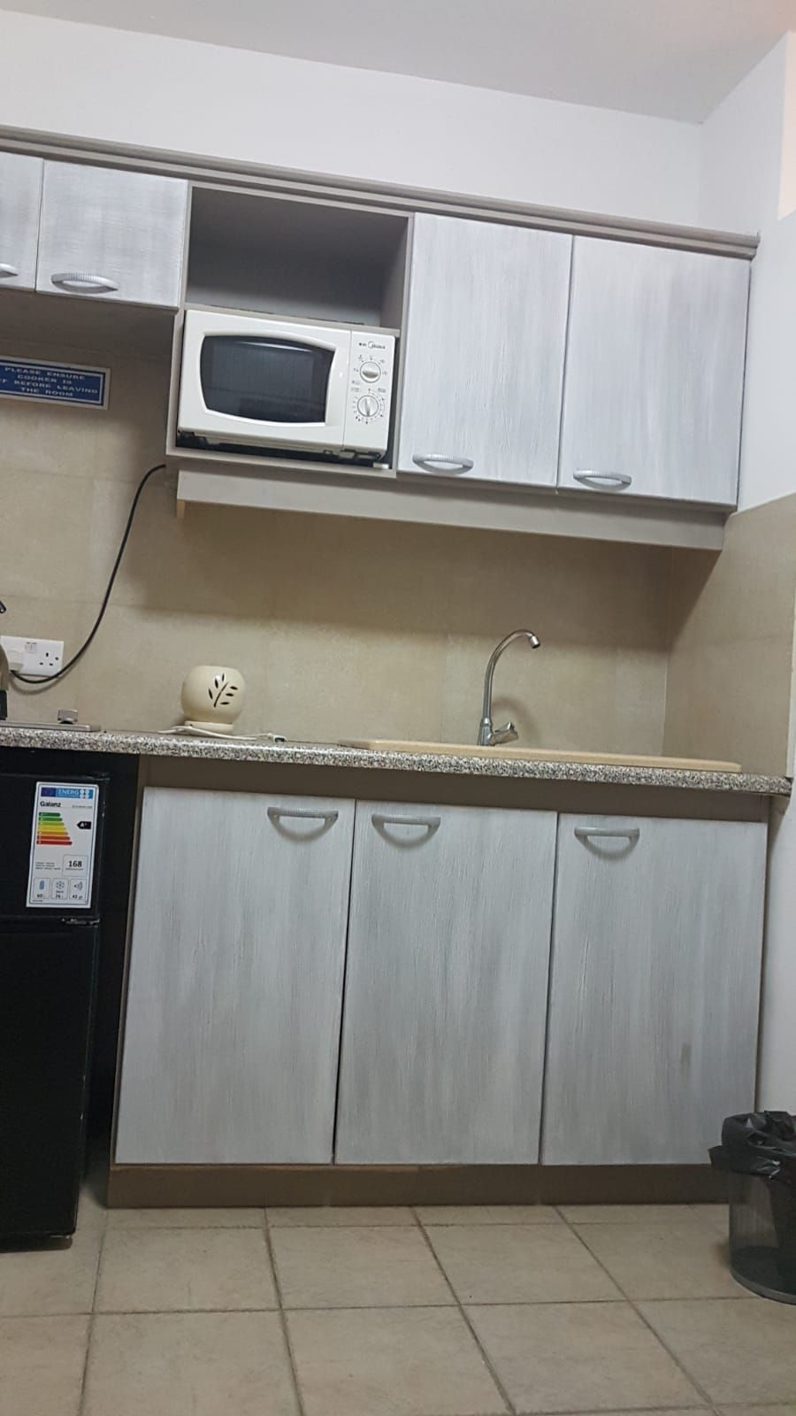 A compact kitchen with a microwave, sink, and cabinets.