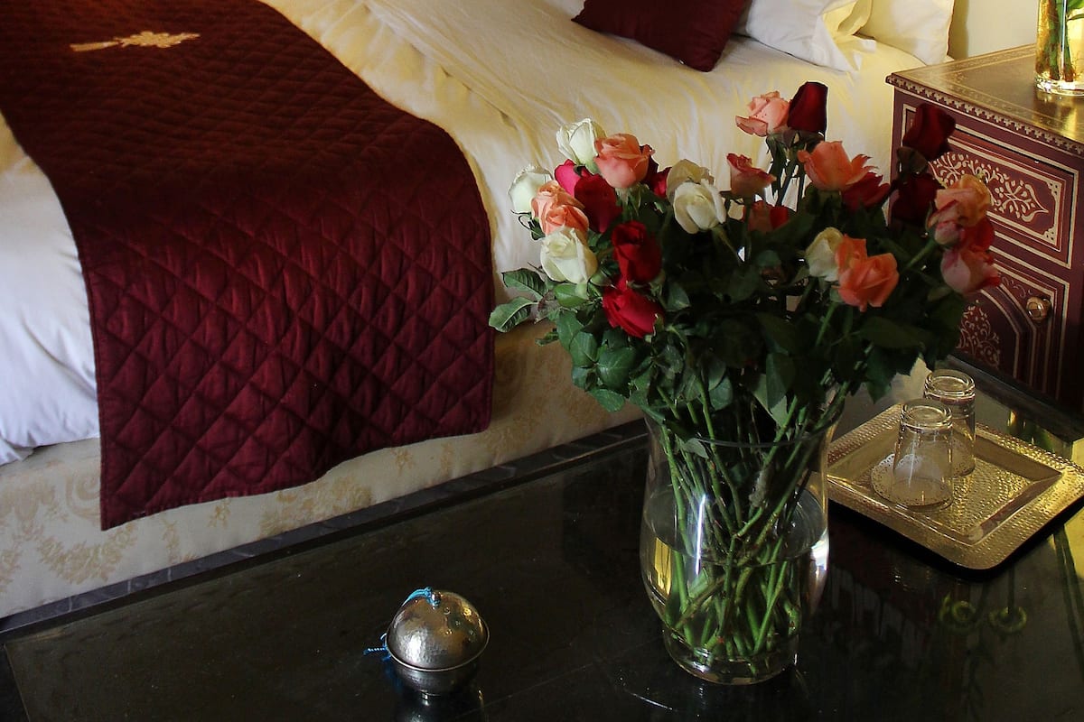 Une chambre d’hôtel avec un lit, un vase de fleurs, une table de chevet et un tableau au mur.