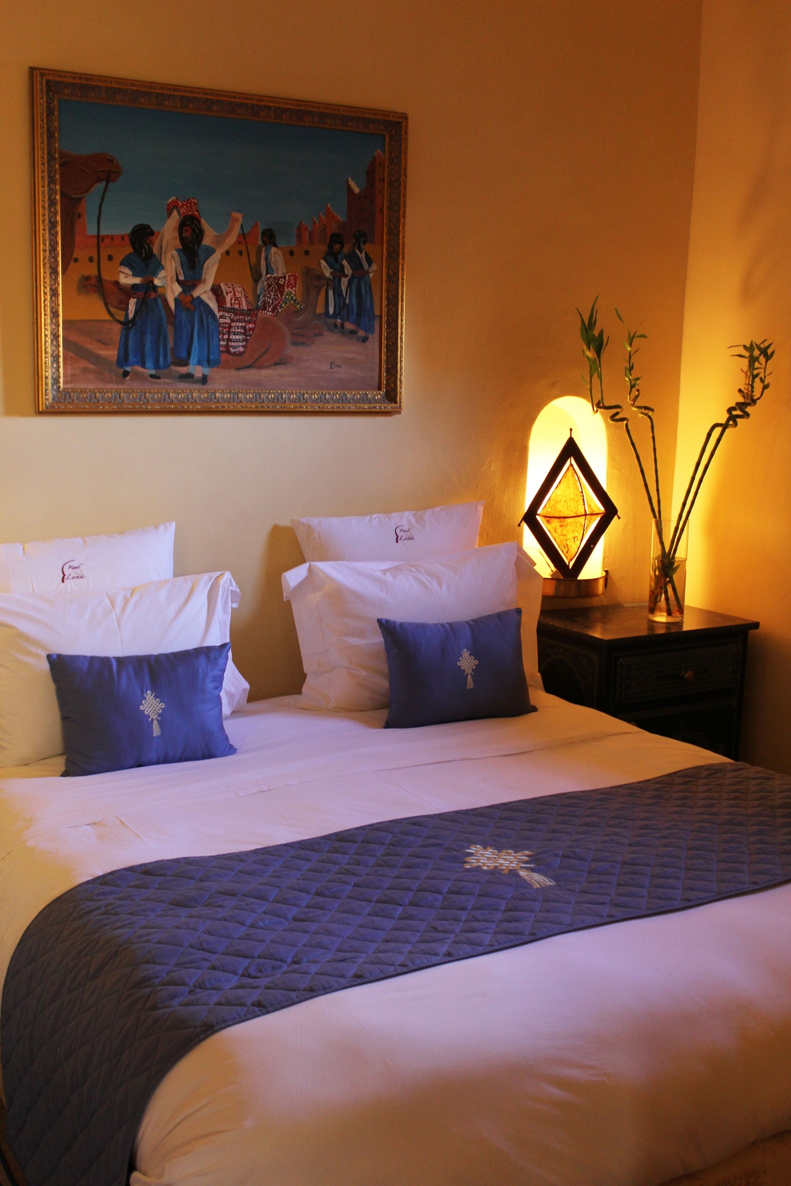 Une chambre d’hôtel avec un grand lit, deux oreillers, un tableau au mur et une table de chevet avec une lampe.
