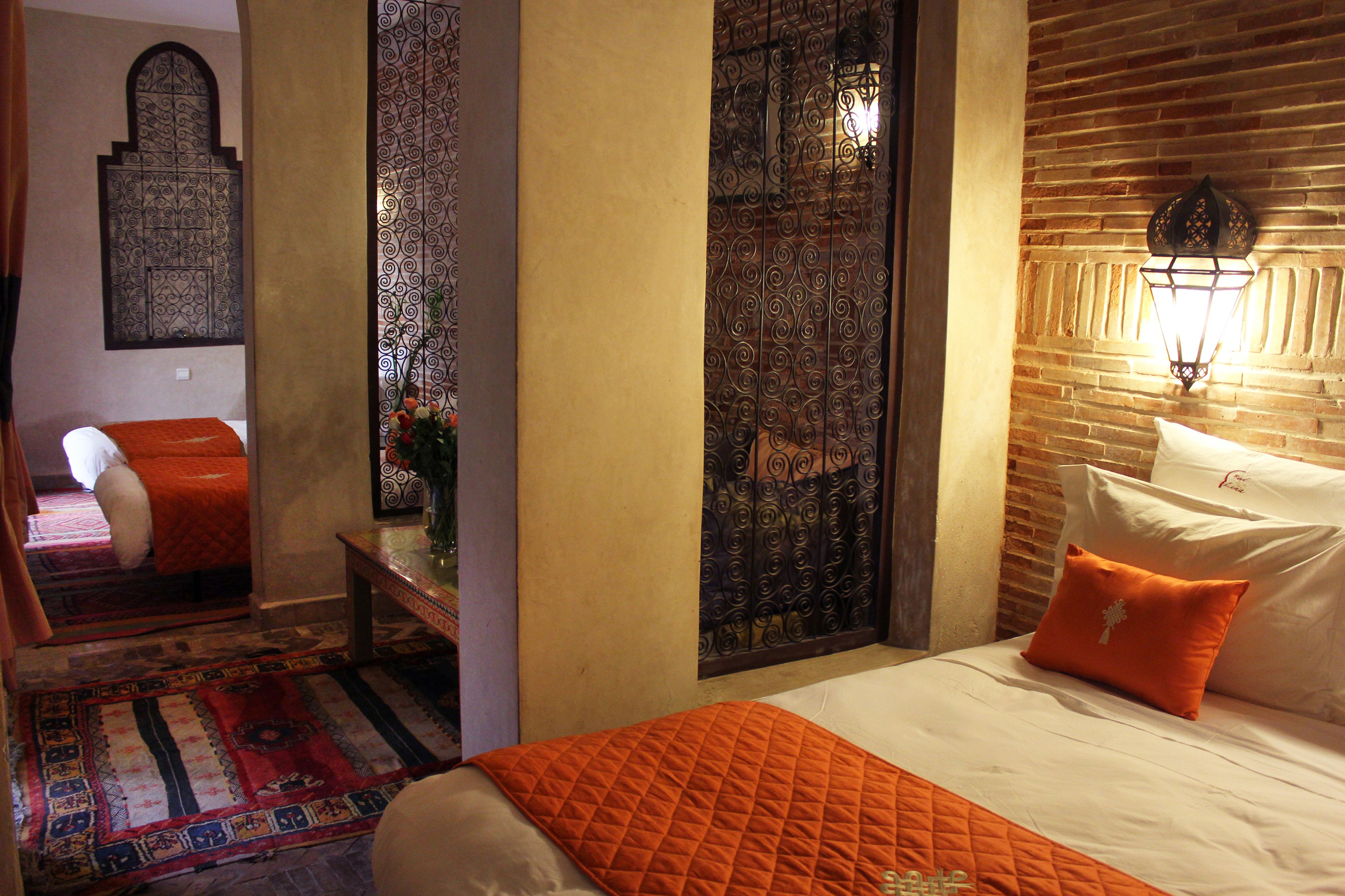 A hotel room with a bed, a nightstand, a decorative wall, and a patterned rug.