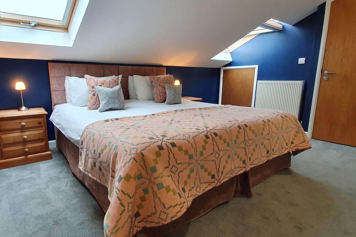 A bedroom with a bed, nightstands, a dresser, a radiator, and a door.