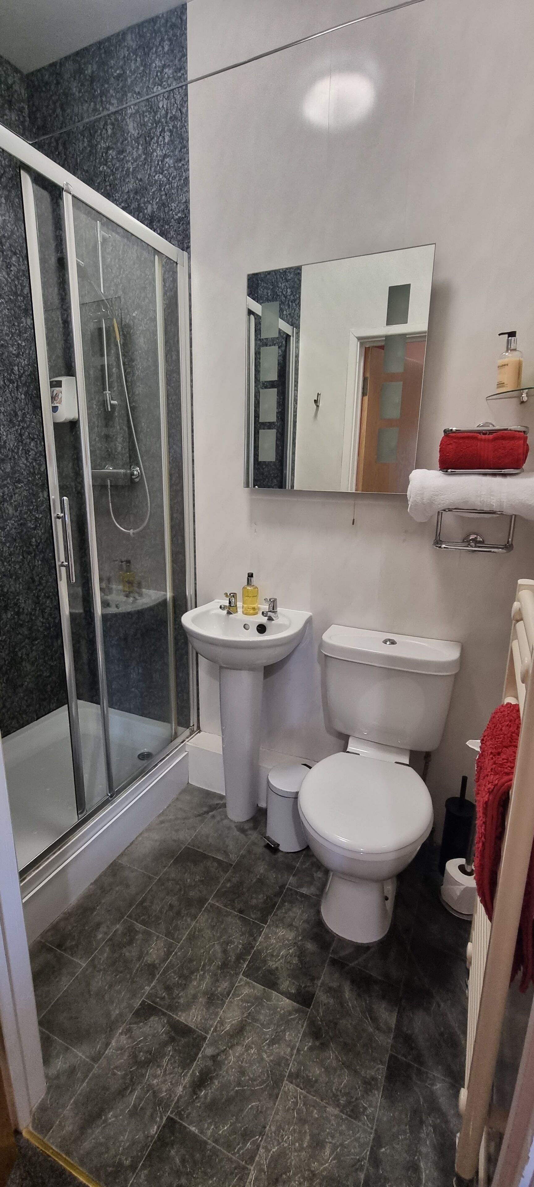 A bathroom with a glass-enclosed shower, a sink, a toilet, and a mirror.