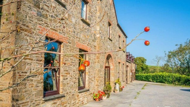 A stone building with arched windows and a paved pathway. - Llety Cynin (Carmarthen)
