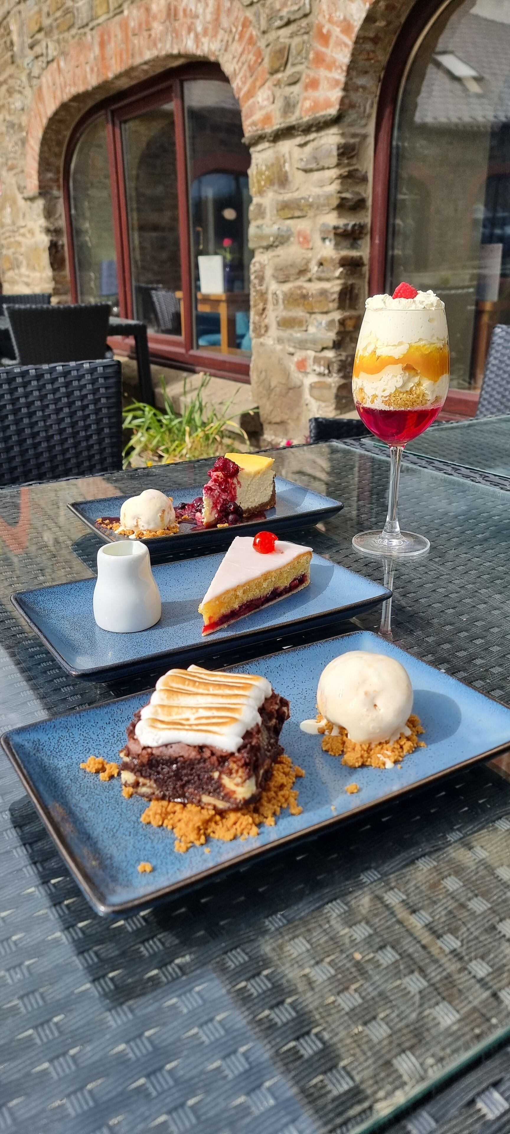 A table with dessert plates, including a slice of pie and a glass of dessert topped with a cherry.