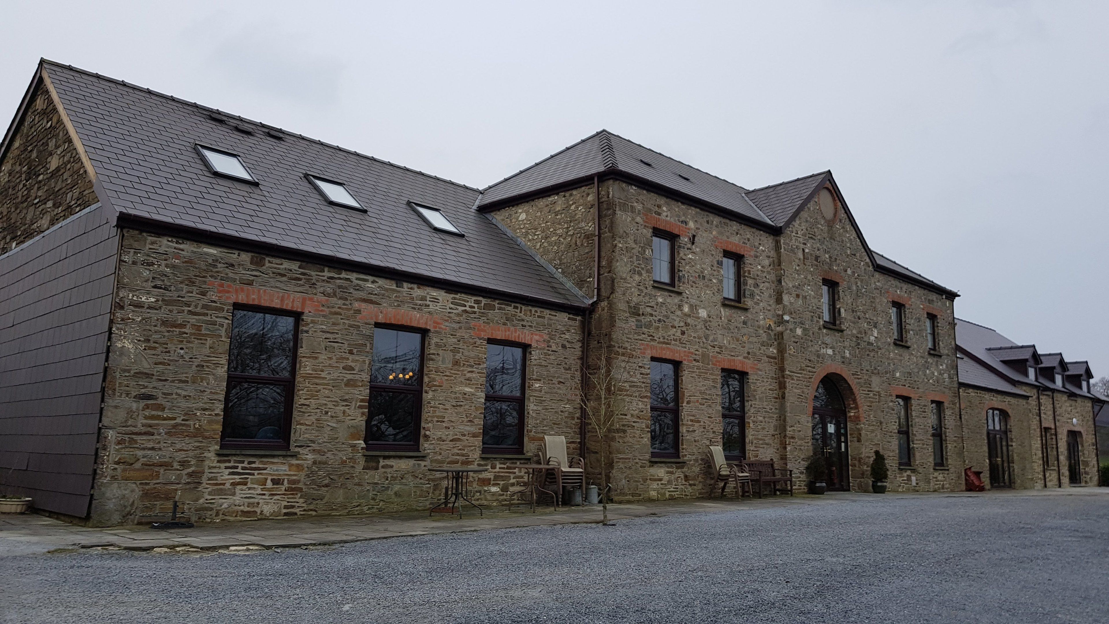 A stone building with multiple windows and a gravel driveway.