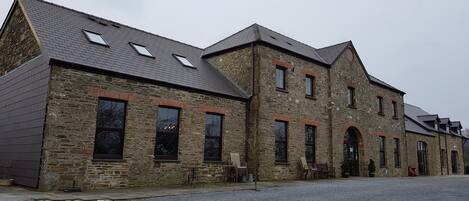 A stone building with multiple windows and a gravel driveway.
