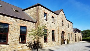 A stone building with multiple windows and a gravel driveway. - Llety Cynin (Carmarthen)