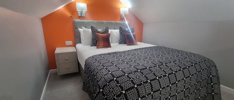 Un dormitorio con cama, mesita de noche y dos lámparas fijadas a la pared.