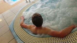 A person relaxing in a hot tub with a view of a swimming pool. - Llety Cynin (Carmarthen)
