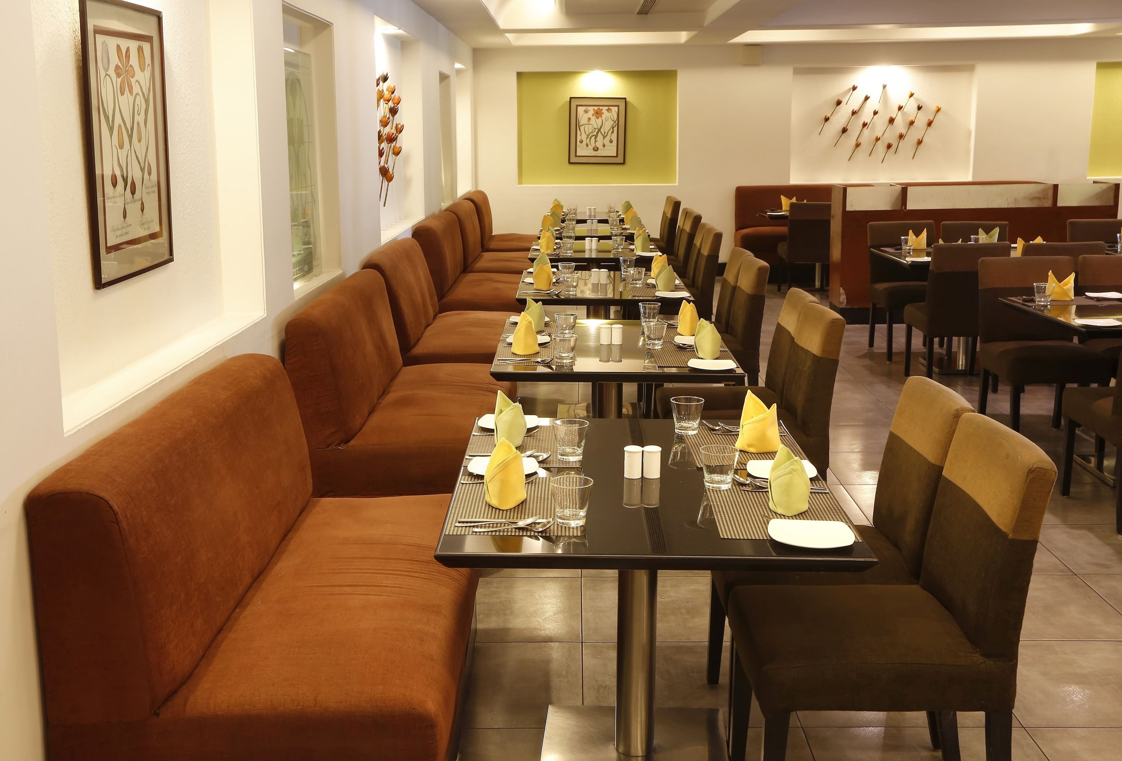 A long dining table set with chairs, a sofa, and framed artwork on the walls.