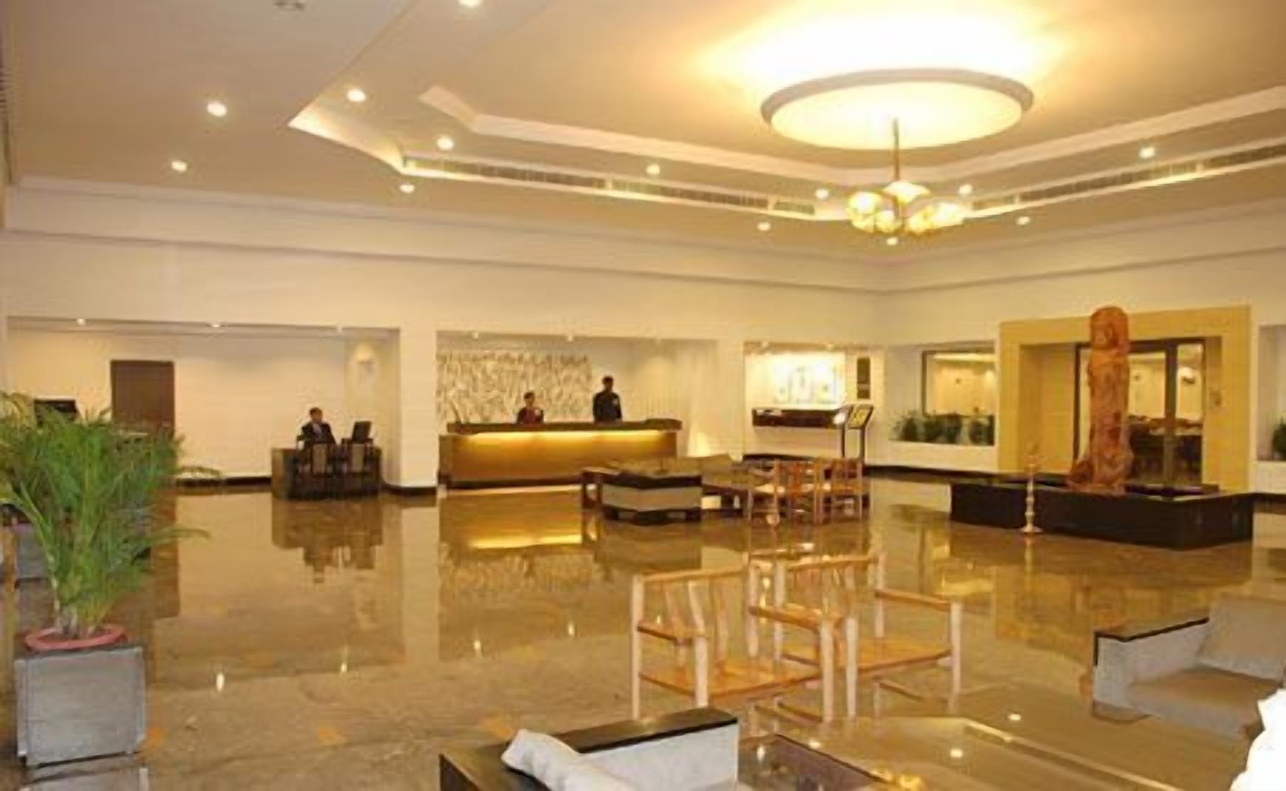 A spacious lobby with a reception desk, seating area, and a large chandelier.
