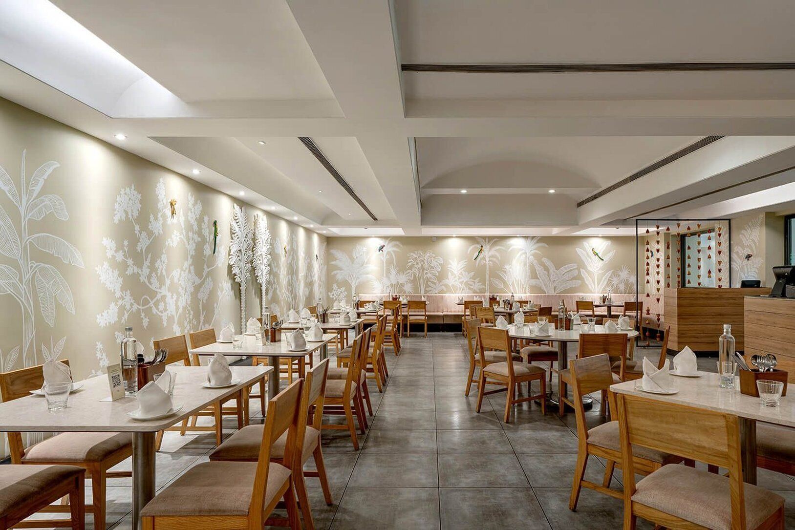 A restaurant with multiple tables and chairs, a modern ceiling design, and decorative wall art.