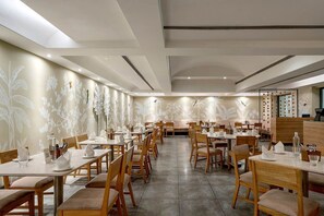 Un restaurante con varias mesas y sillas, un diseño de techo moderno y decoración en las paredes.