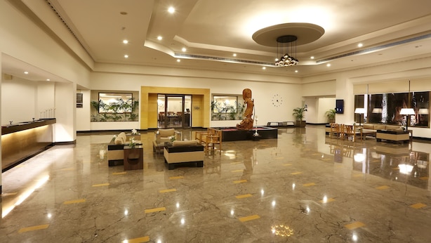 A spacious lobby with a reception desk, seating area, and a large statue.