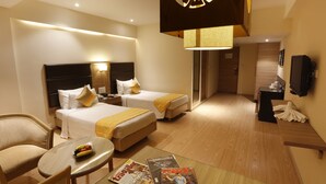 A hotel room with two beds, a sitting area with a table, and a TV.