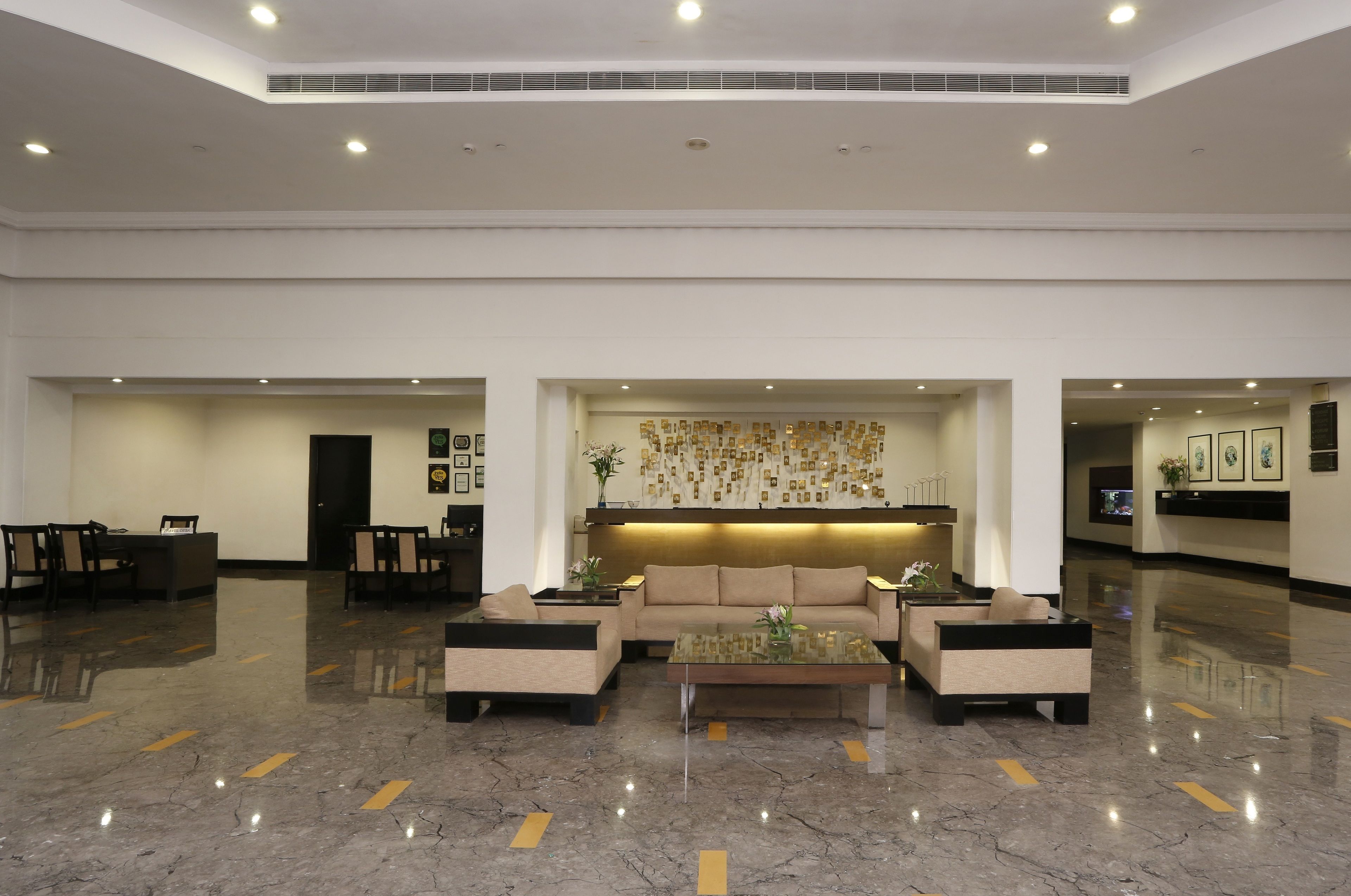 A spacious lobby with a reception desk, seating area, and a decorative wall.